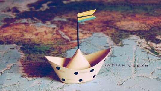 Ein Papierboot auf einer Weltkarte.