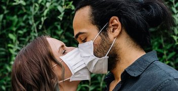 Eine Mann und ein Frau küssen sich mit einer Maske.