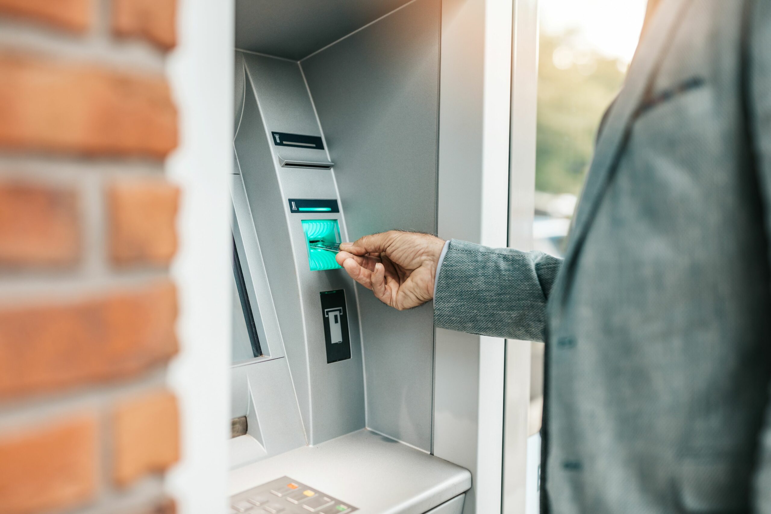 Eine Person schiebt ihre Bankkarte in den Schlitz am Geldautomaten.