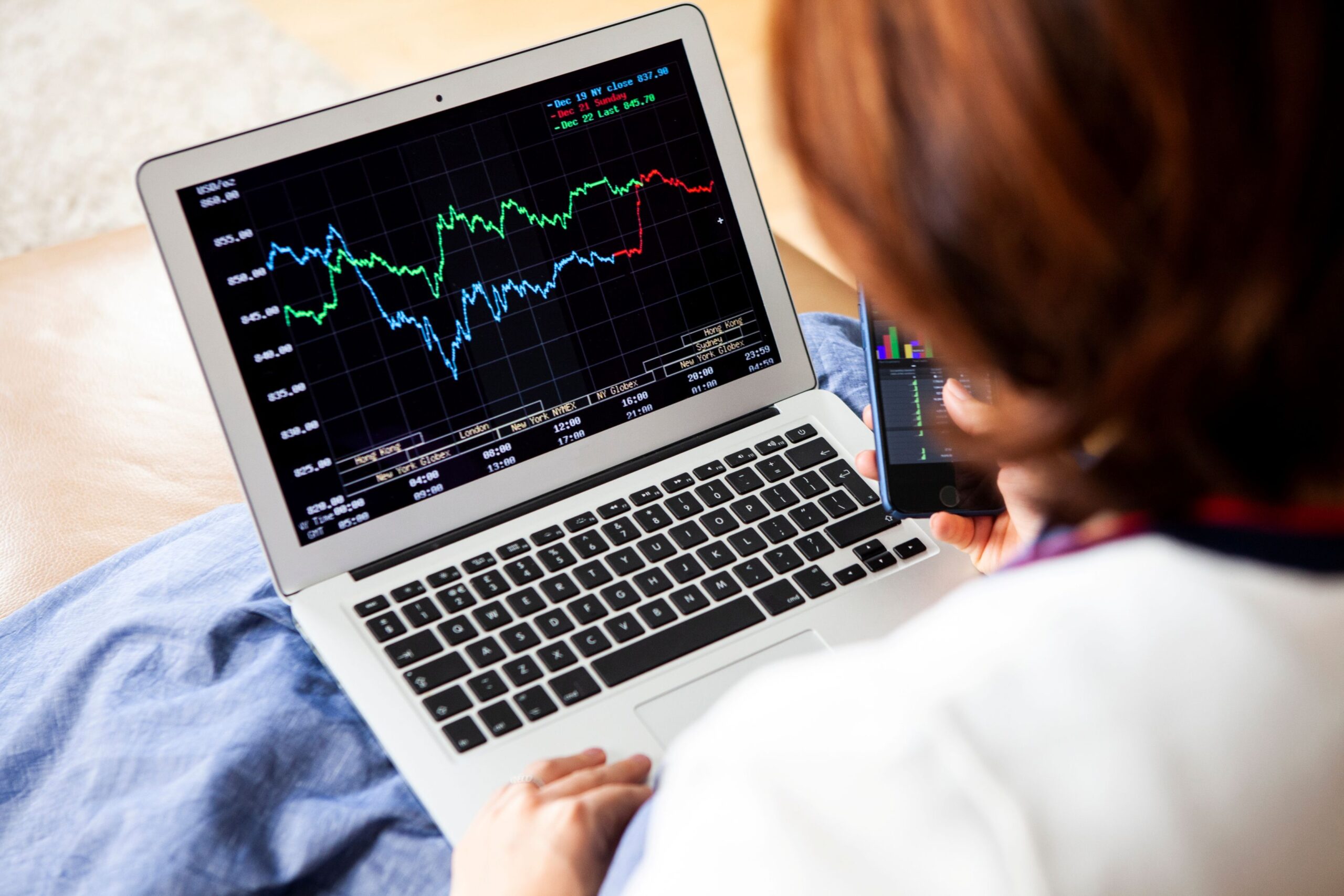 A woman is looking at a stock chart on her laptop screen.