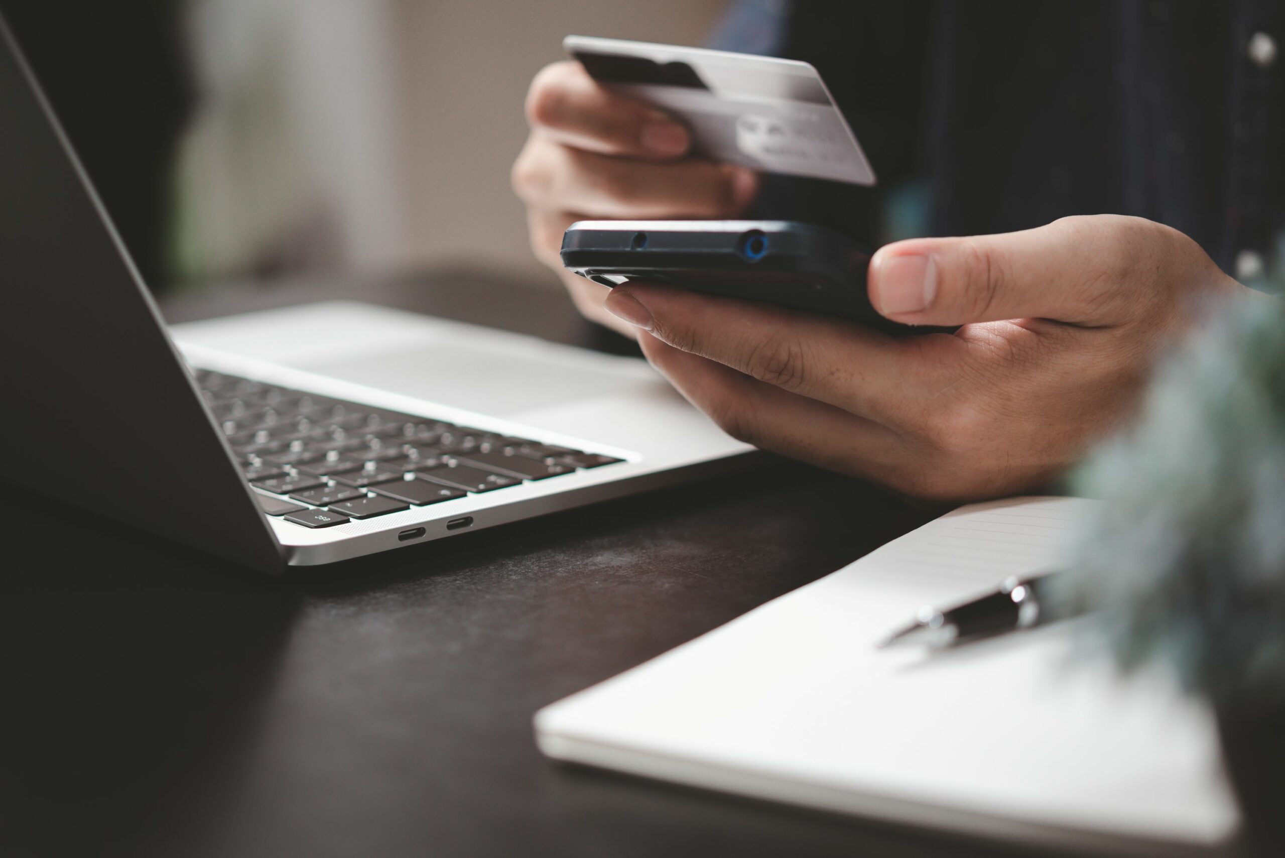 Eine Person hält Kreditkarte und Smartphone bereit, um online eine Bestellung zu bezahlen.
