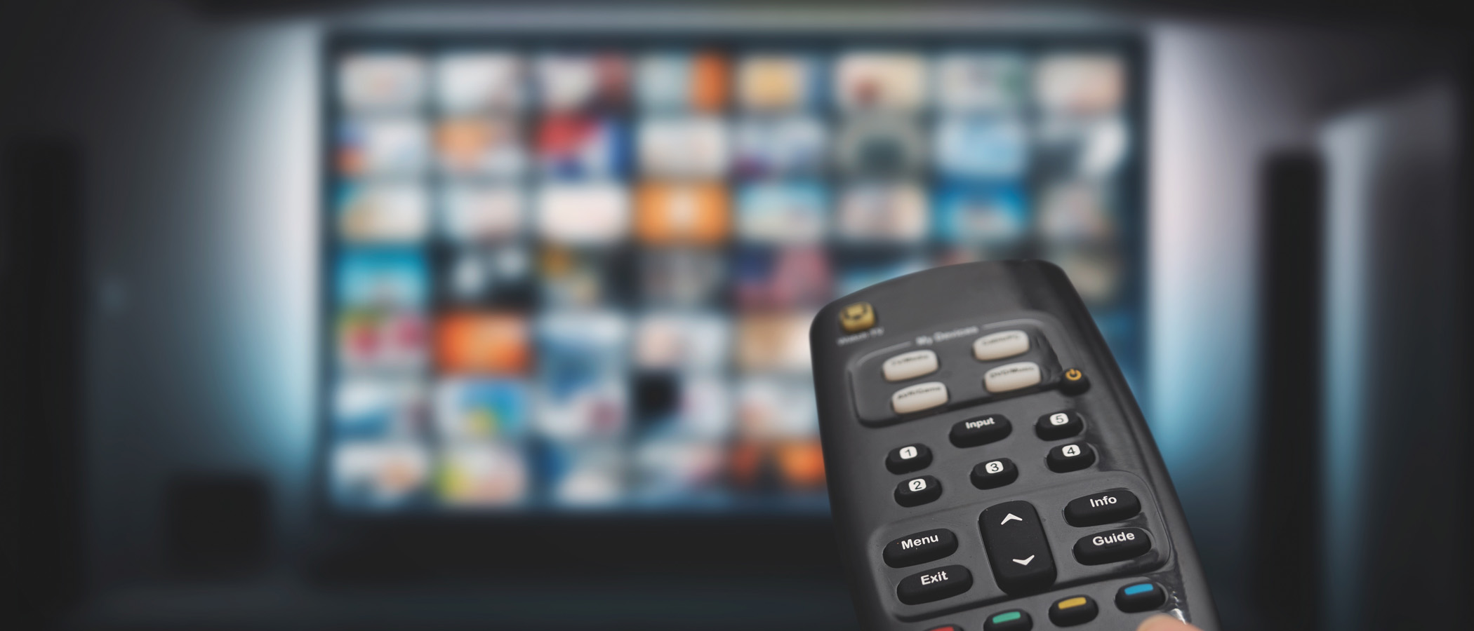 Fernbedienung mit dem Fernseher im Hintergrund, auf einer Streaming-Plattform.