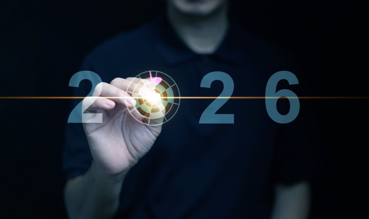 Mann visiert mit einem Dartpfeil die 2026 an