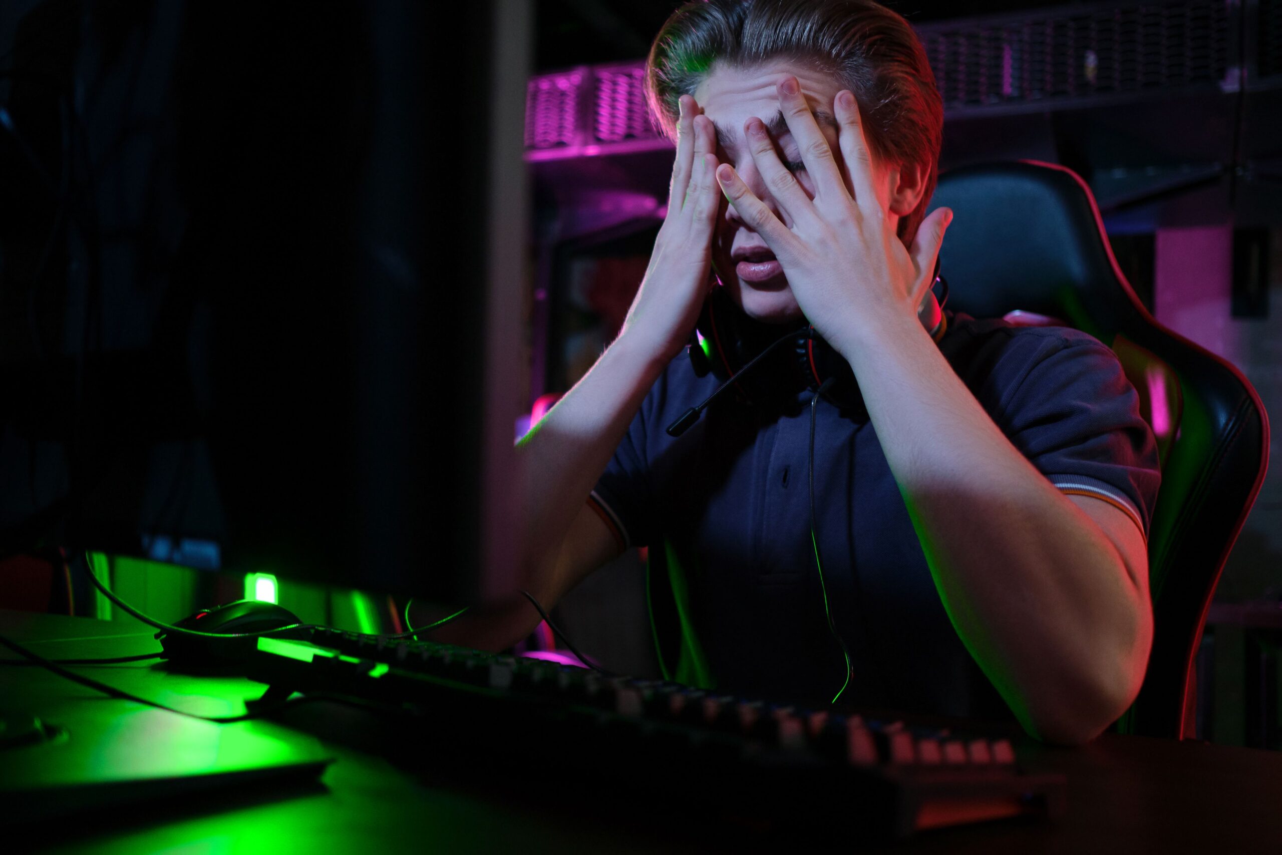 Ein Mann sitzt am Schreibtisch vor seinem Computer und hält sich vor Frust die Hände vor das Gesicht.