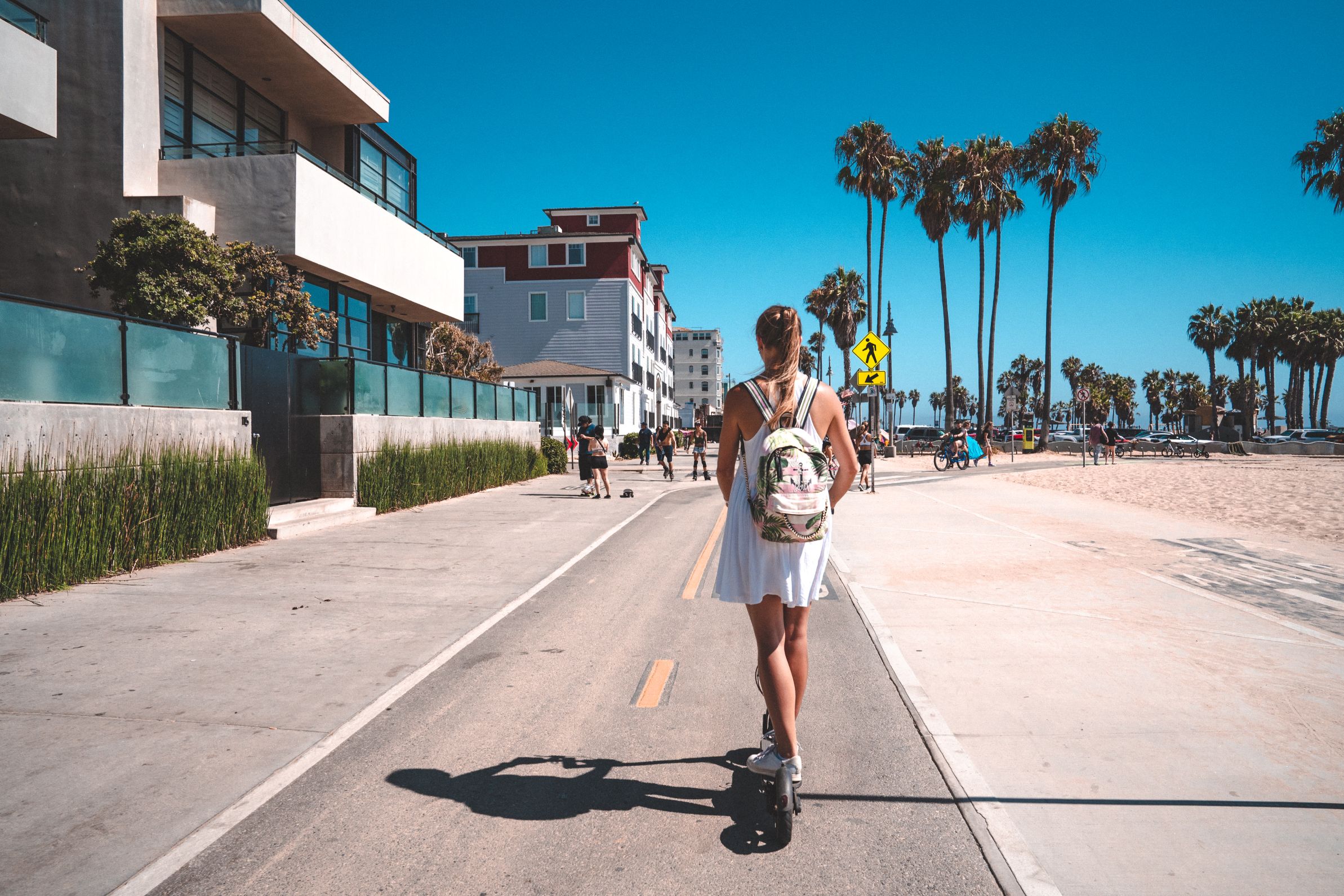 A woman is riding an e-scooter along the beach promenade.