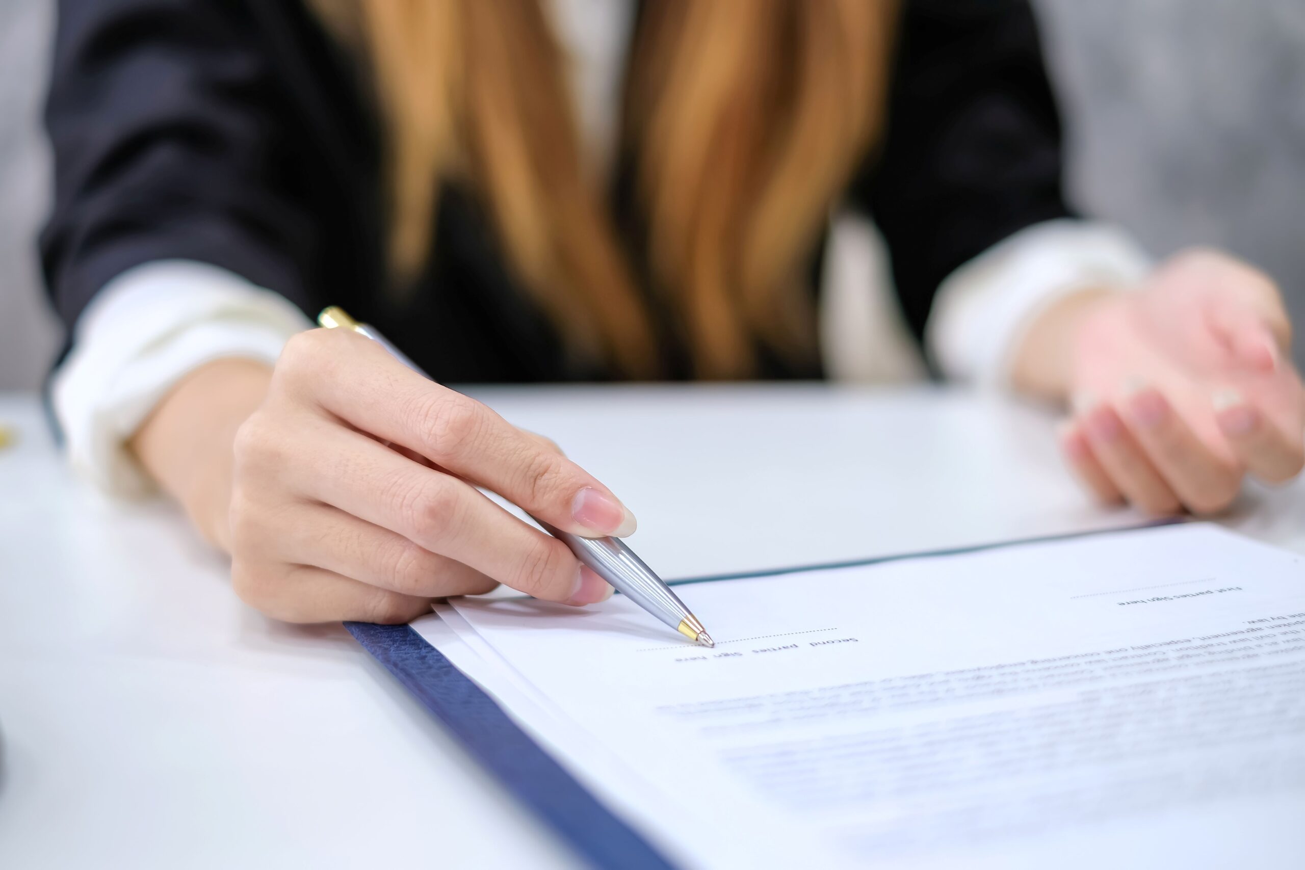 Eine Frau unterzeichnet einen schriftlichen Vertrag