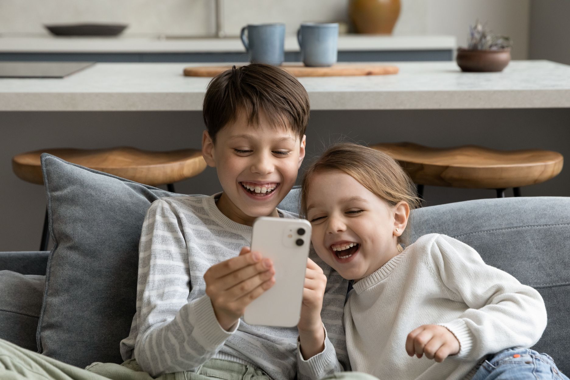 Ein kleiner Junge und ein Mädchen spielen am Smartphone.