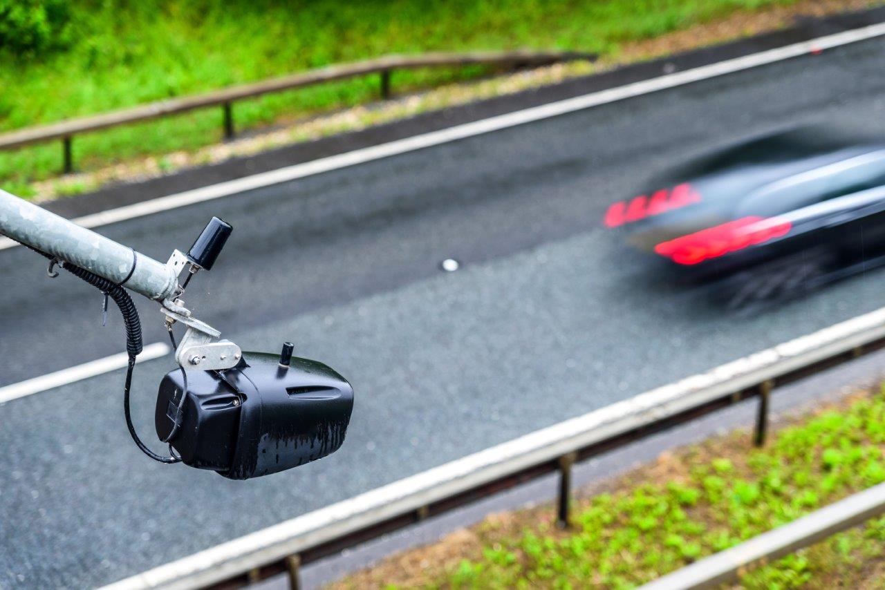 A traffic surveillance camera films cars on the road.