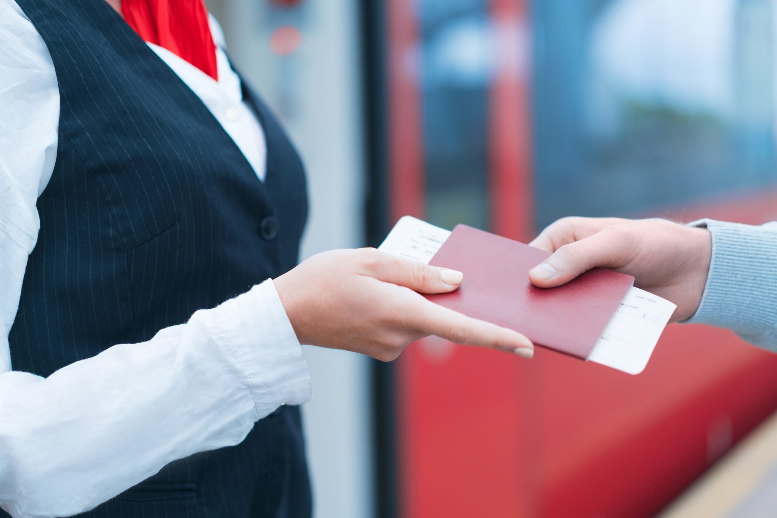 Nahaufnahme einer Hand, die einer Zugbegleiterin ein Zugticket und Pass überreicht