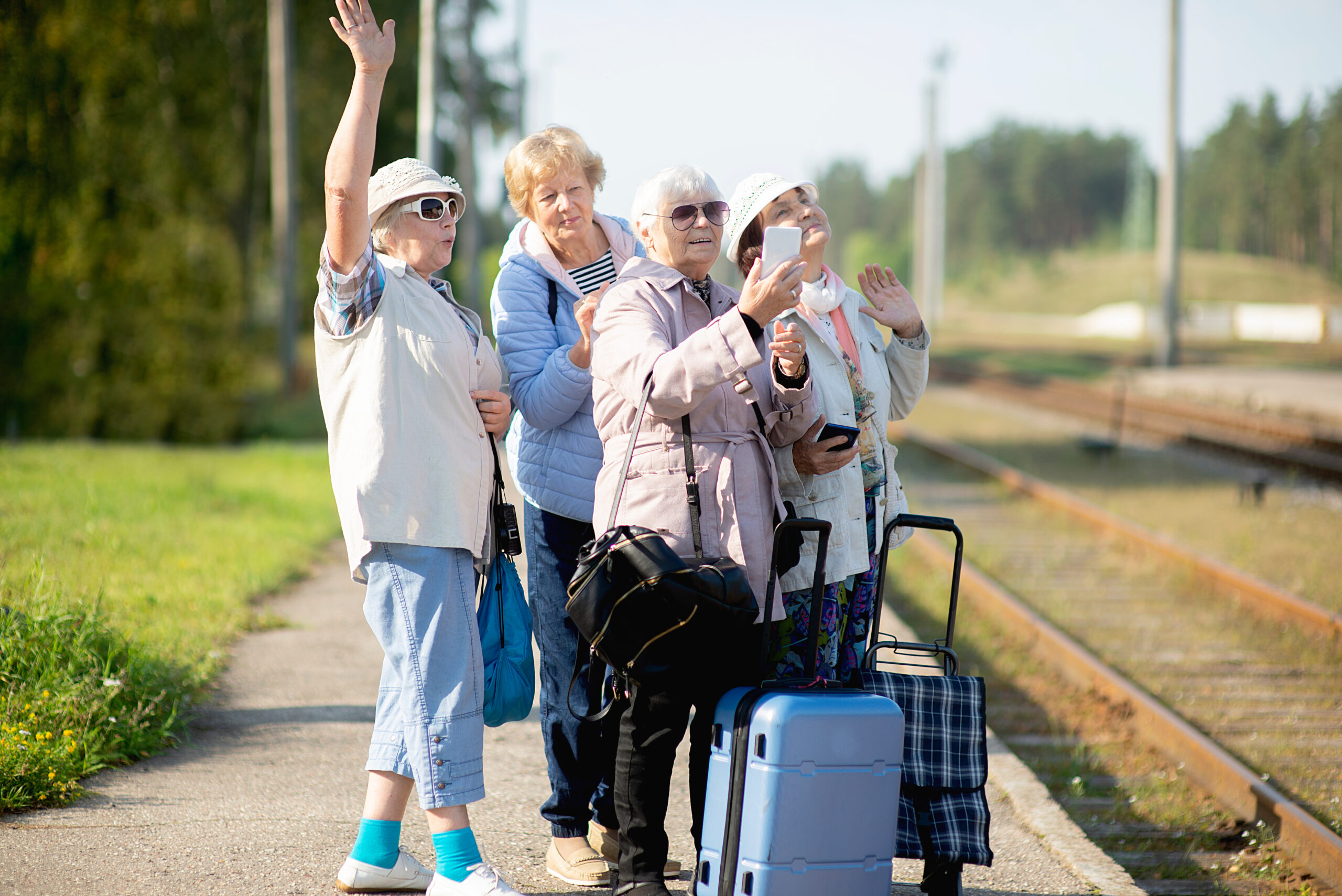 Eine Gruppe von Rentnerinnen steht am Bahngleis und wartet gut gelaunt auf den Zug
