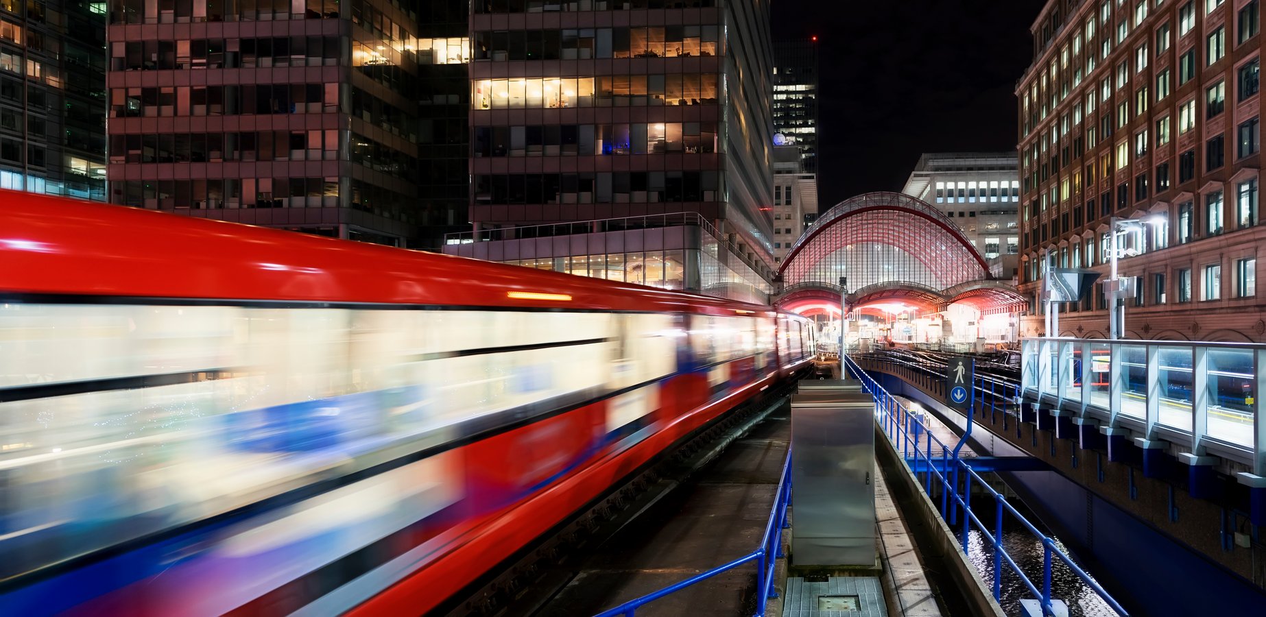 Roter Zug fährt nachts aus einem Bahnhof