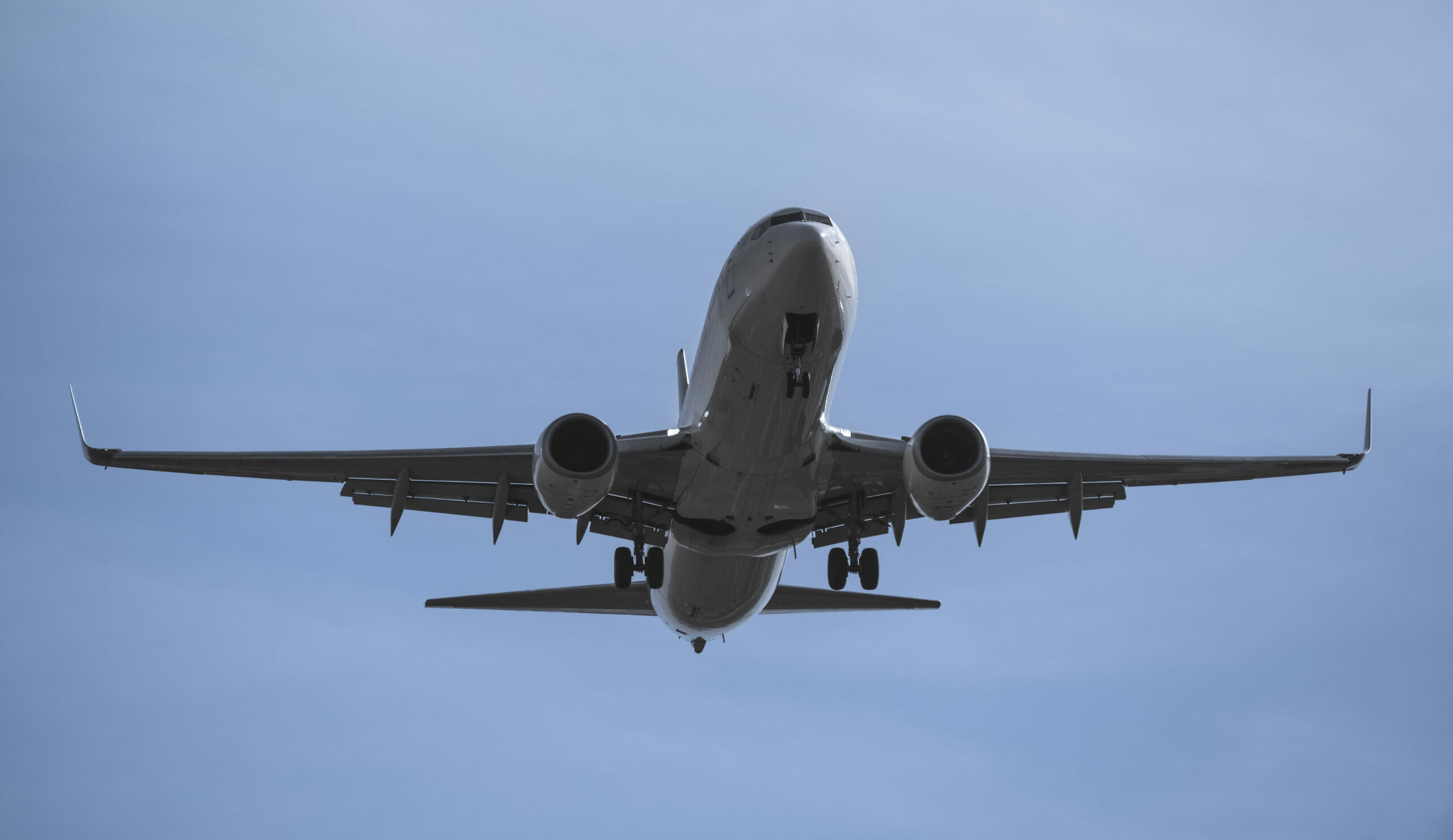 Close-up of an plane in flight, viewed from below against a blue sky
