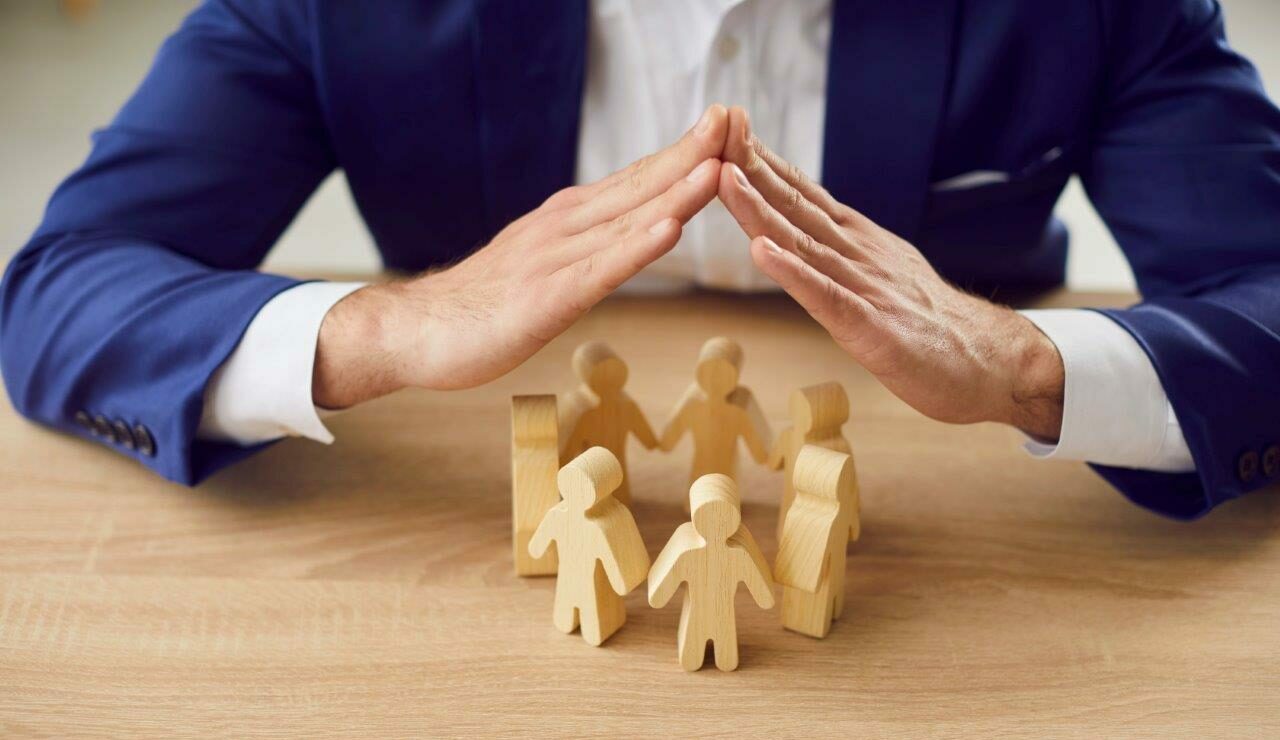 A man is holding his hands protectively over a group of figures.