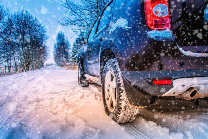 Car is parked on a snow-covered country road.
