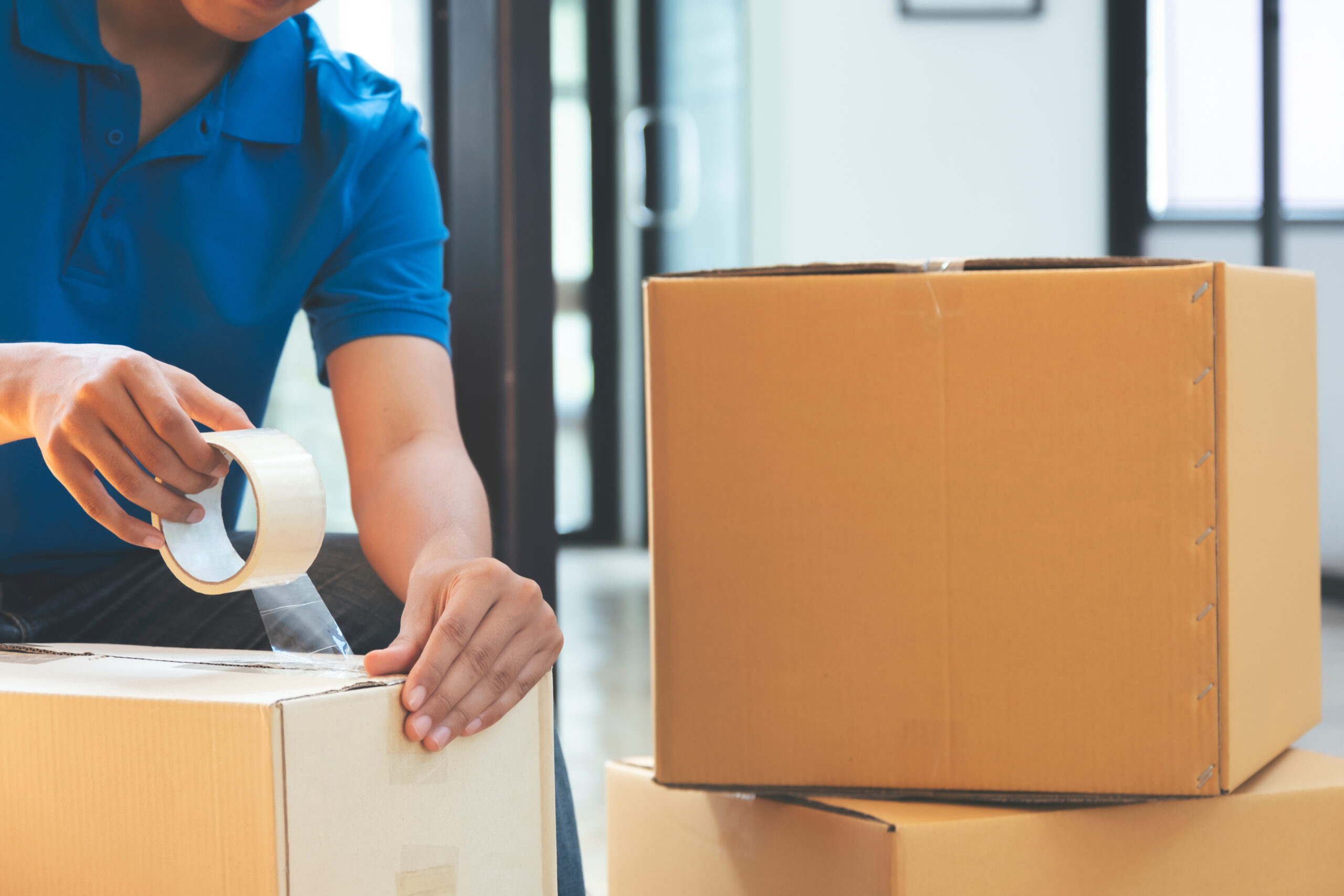 A man seals several packages with adhesive tape.