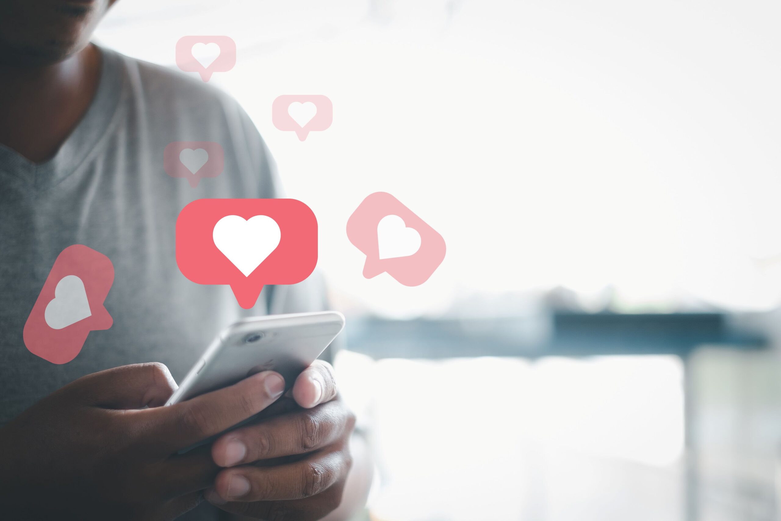 Eine Person tippt auf dem Smartphone in einer Online-Datingplattform Nachrichten, symbolisiert durch rosafarbene Nachrichtensymbole mit Herz.