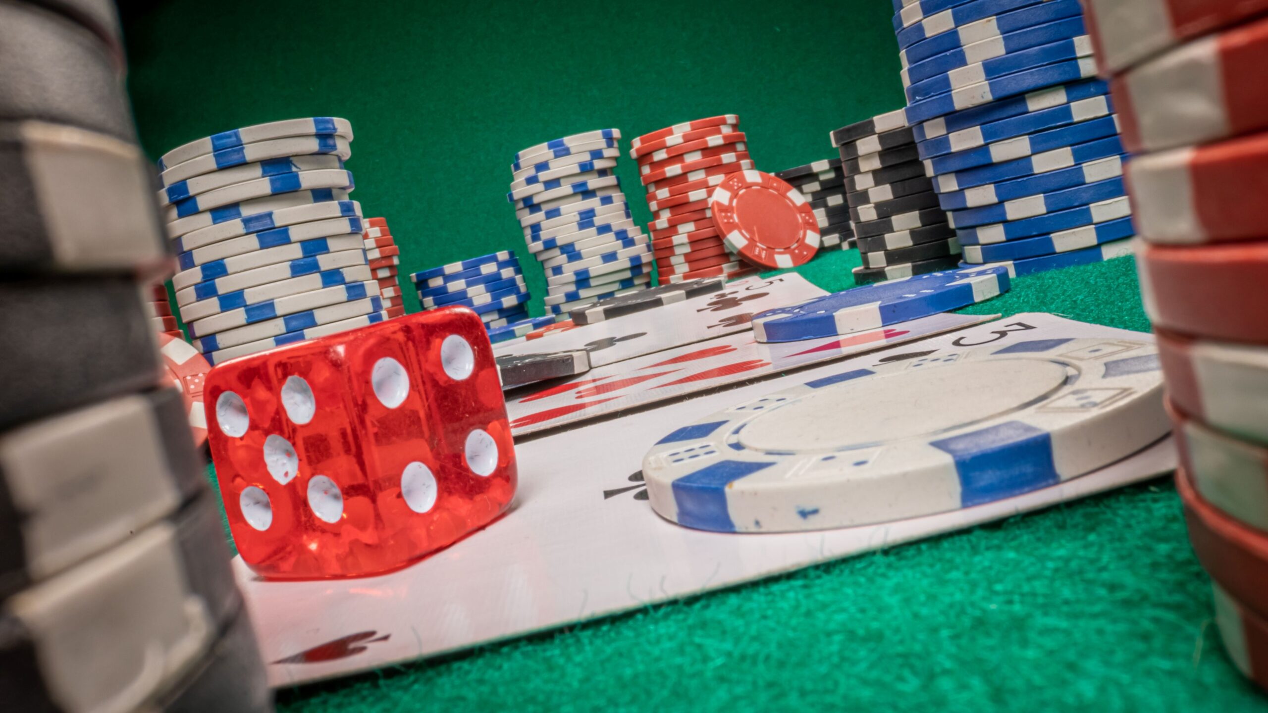 Würfel, Poker-Chips und Karten liegen auf dem Pokertisch.