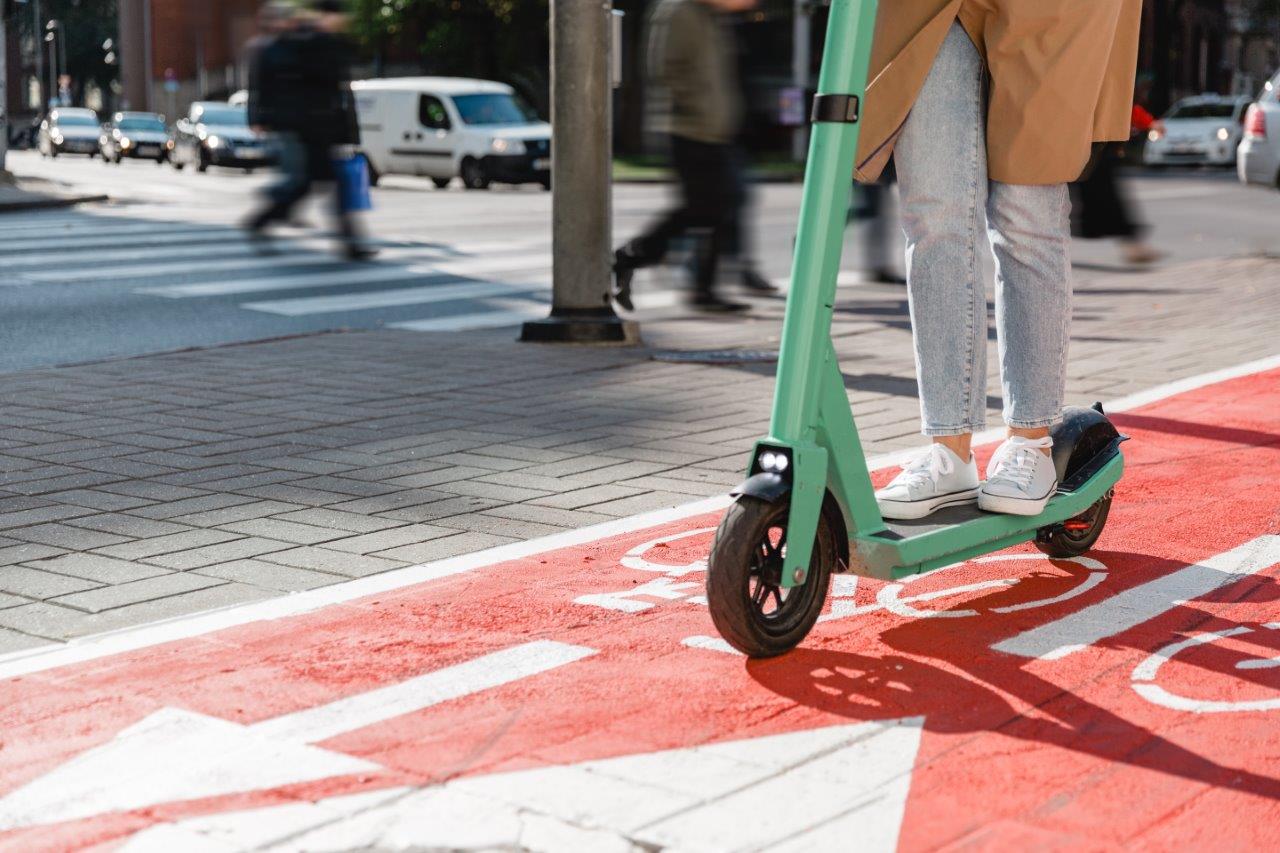 Someone is riding an e-scooter on a road in city traffic.