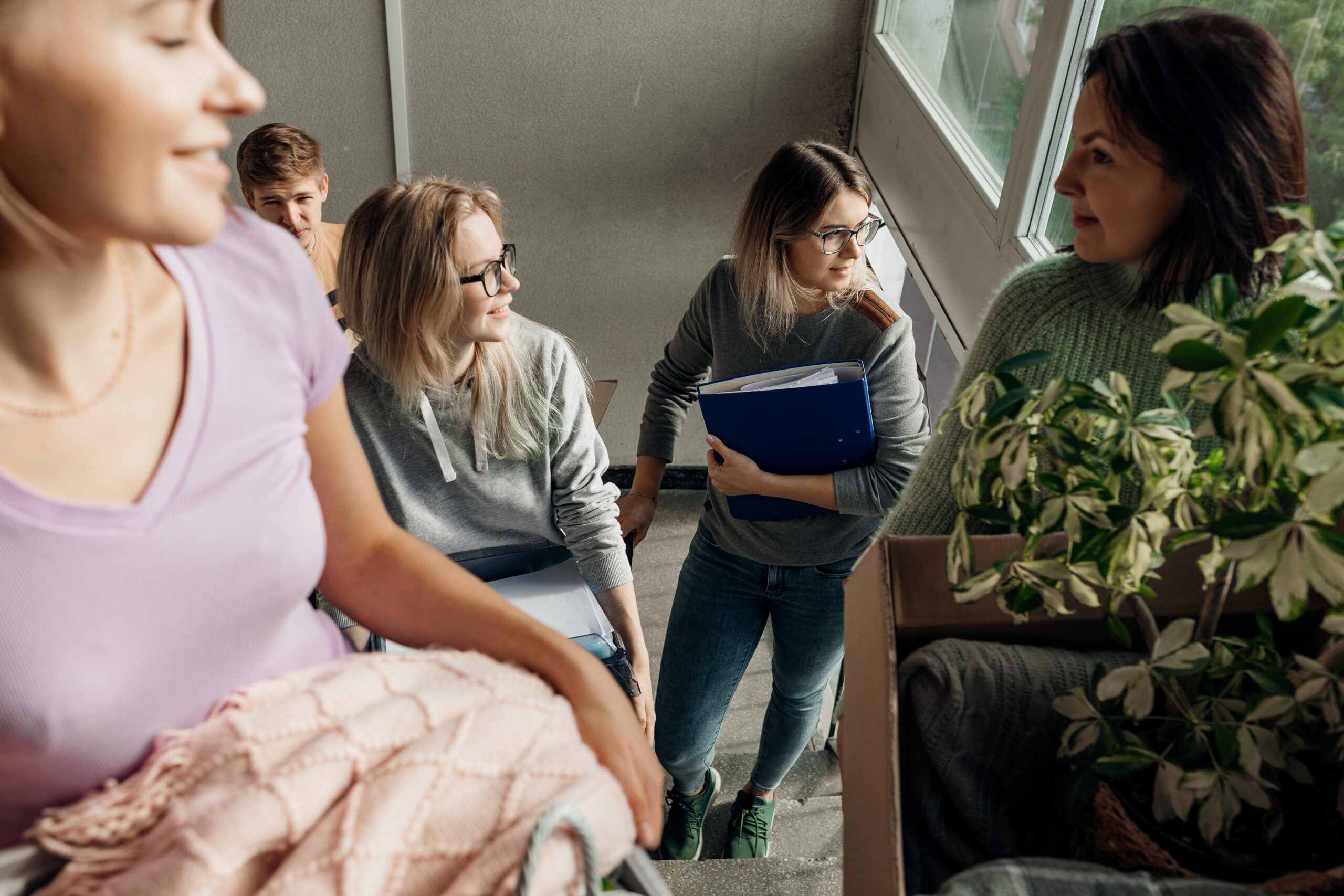 Fünf Studierende tragen Umzugskartons die Treppe hoch