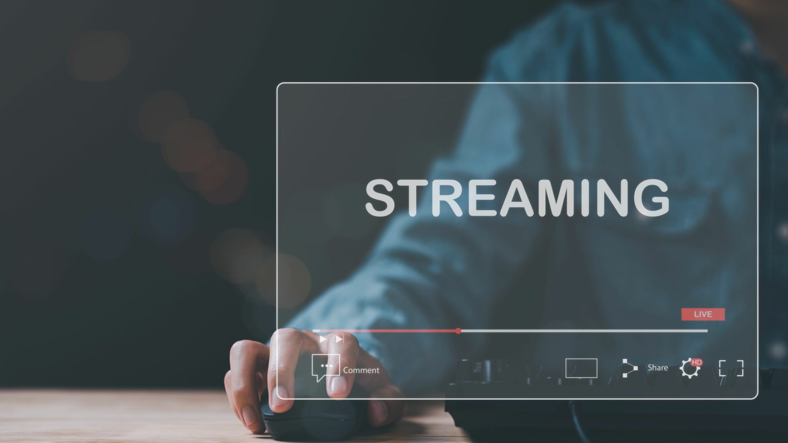 Bildschirm mit der Aufschrift „Streaming“ im Vordergrund, dahinter ein Mann mit einer Computermaus.