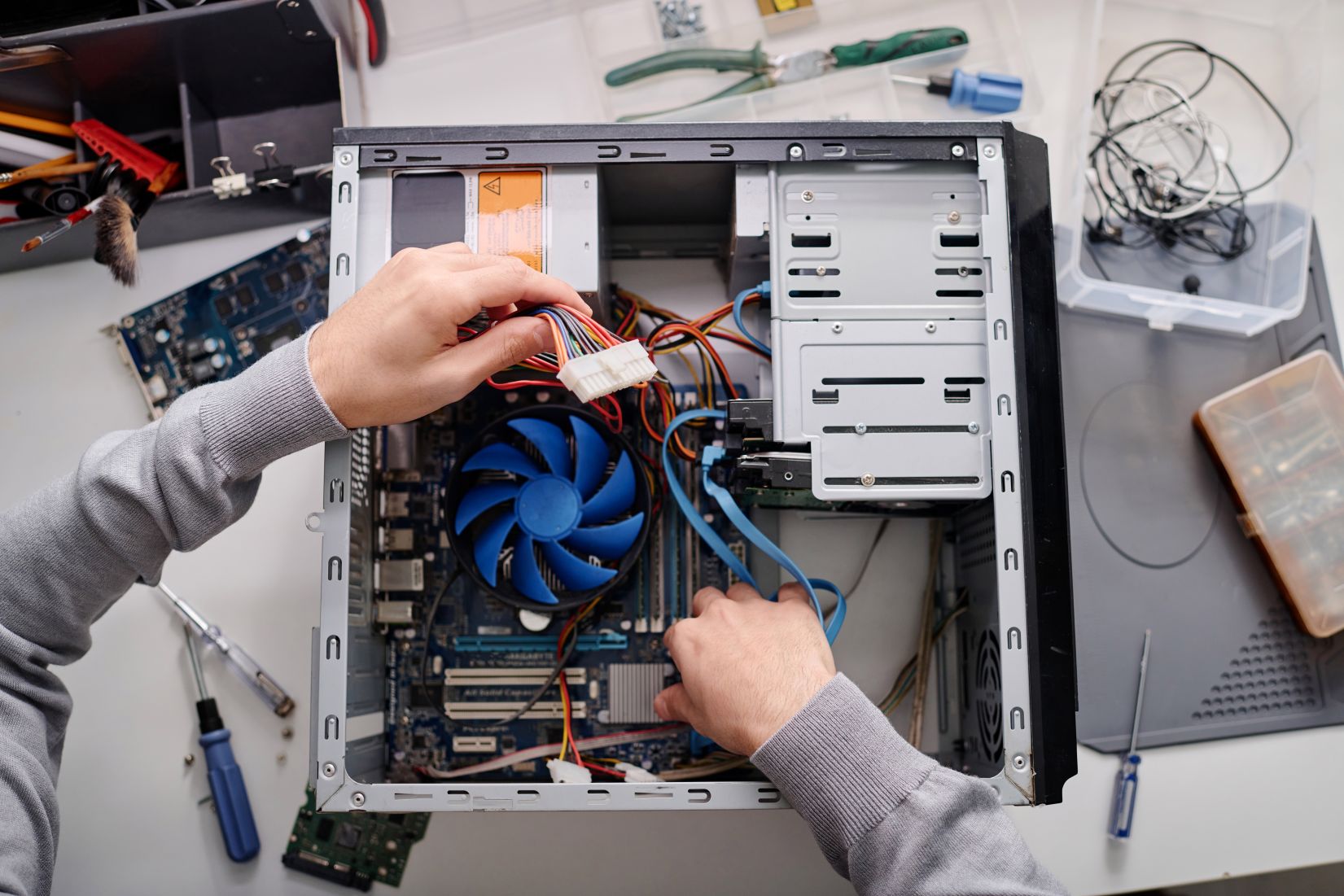 Ein Techniker repariert das einen Desktop-PC und hält die Kabel aus dem Gehäuse in der Halt.