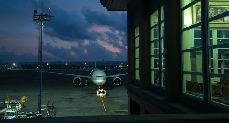 Ein Flugzeug steht bei Nacht auf einer Parkposition an einem Flughafen.