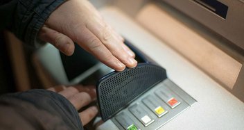 Eine Person hebt an einem Bankautomaten Geld von seinem Konto ab.