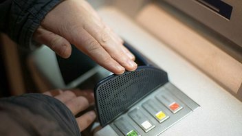 Eine Person hebt an einem Bankautomaten Geld von seinem Konto ab.