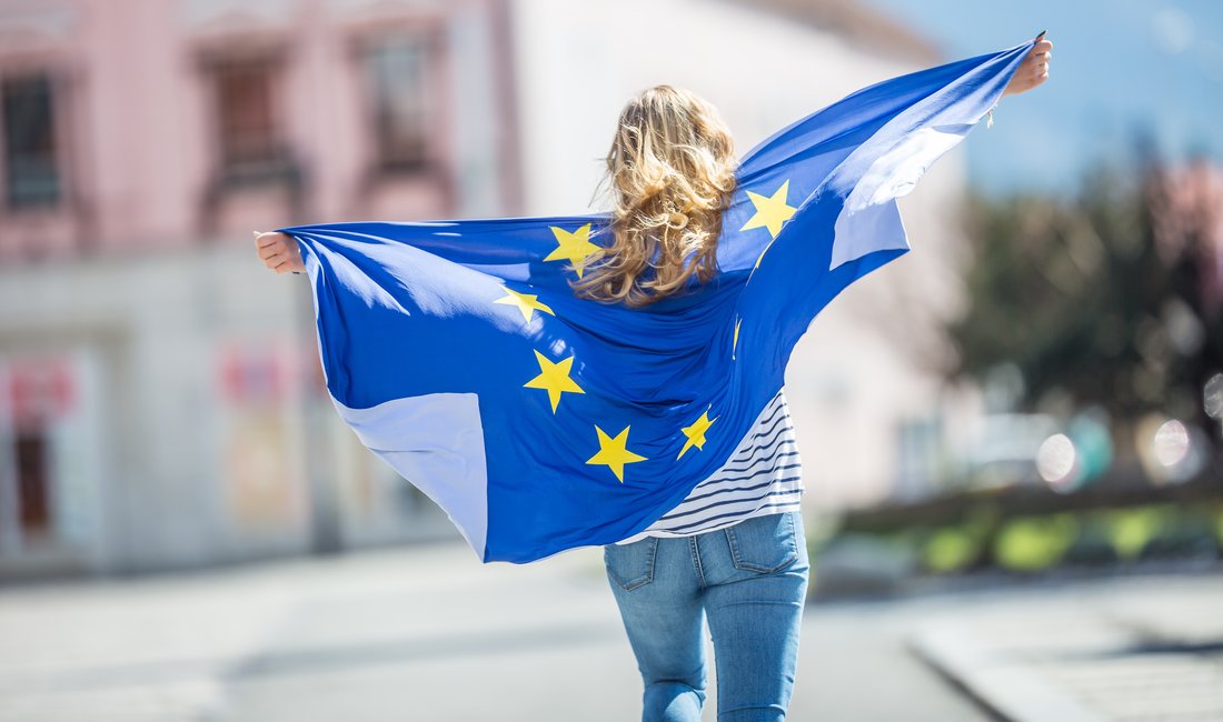 Eine junge Frau trägt die EU-Fahne wie einen Umhang.
