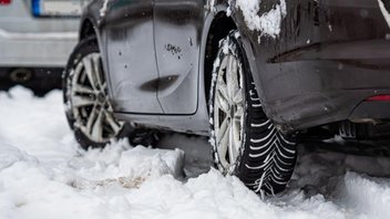 Auto mit Winterreifen auf verschneiter Straße 