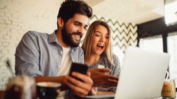 Ein Mann und eine Frau lachend vor einem Laptop