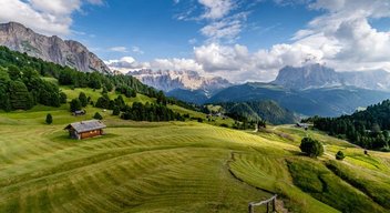 Eine grüne Berglandschaft mit Holzhütten in den Alpen (Italien).