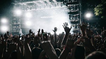 Das Foto zeigt eine Konzertbühne. Im Vordergrund sieht man gestreckte Hände. Das Bild illustriert einen Artikel zu Betrug auf Viagogo, Ticketbande, Fansale und anderen Ticketbörsen.