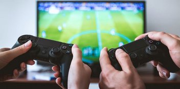 Videospiele: Zwei Personen spielen FIFA auf der Playstation.