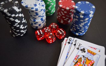 Auf einem Casino-Tisch liegen Würfel, Jetons und Poker-Karten.