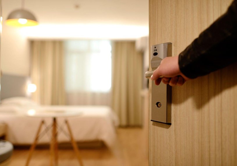 Eine Person öffnet eine Tür zu einem Hotelzimmer.