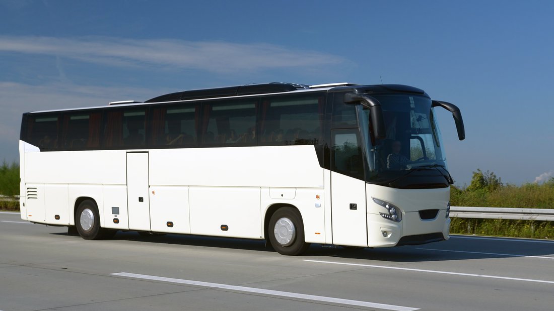 Ein weißer Reise- oder Fernbus der auf einer Straße fährt