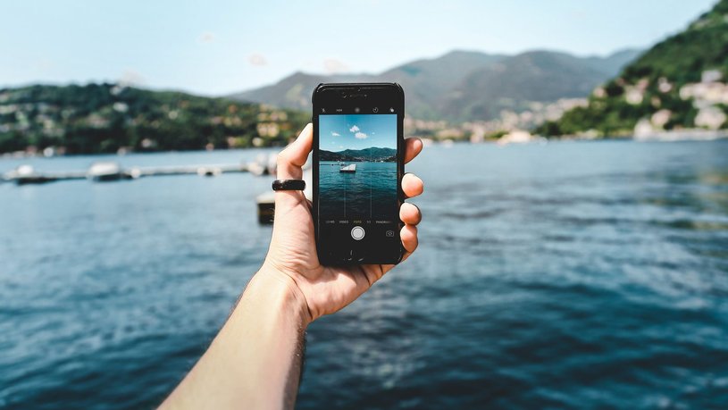 Eine Person macht mit ihrem Smartphone ein Foto vom Meer.
