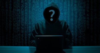 Ein Hacker sitzt in einem dunklen Raum vor einem Laptop.