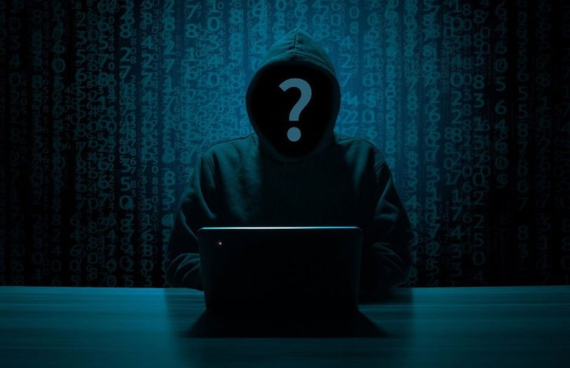 A hacker sits in a dark room in front of his laptop.