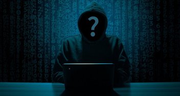 Ein Hacker sitzt in einem dunklen Raum vor einem Laptop.