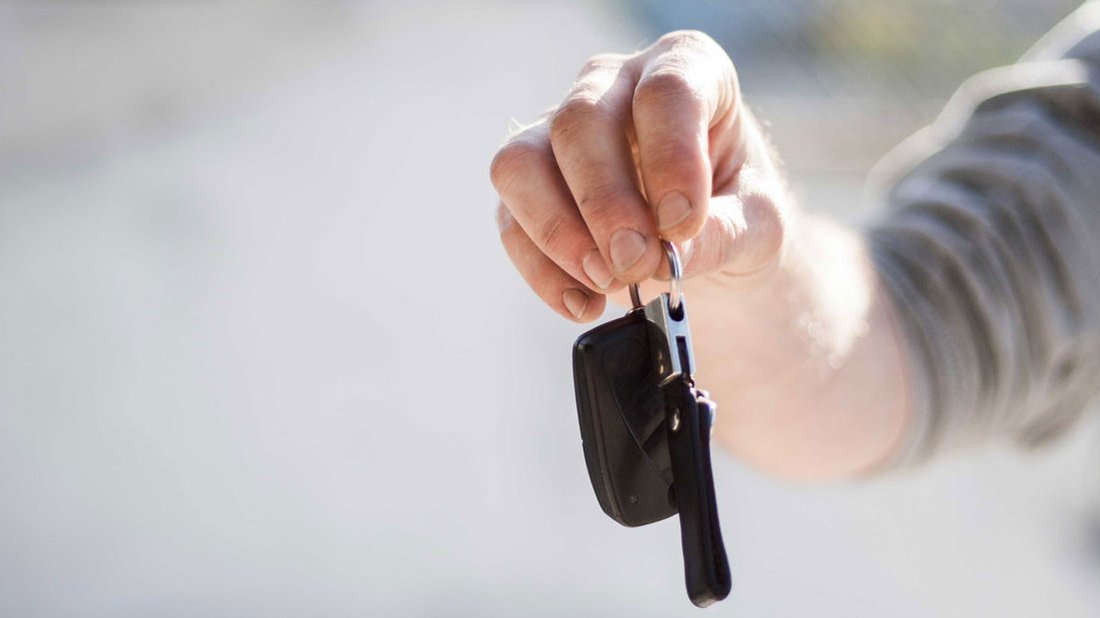Eine Person hält einen Autoschlüssel in der Hand.
