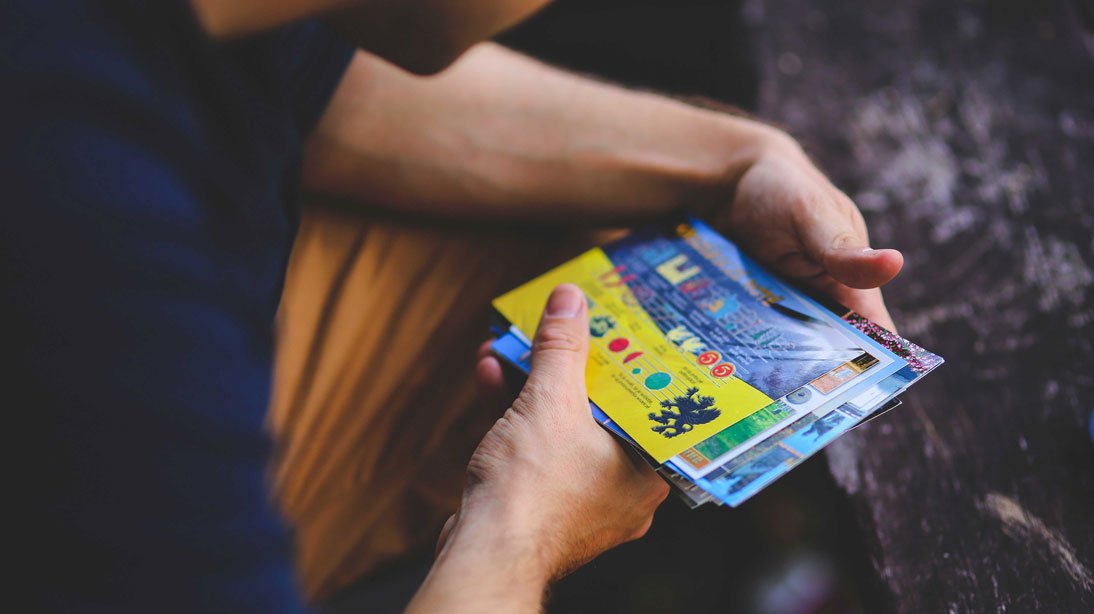 Das Foto zeigt einen Mann, wie er auf Konzertkarten blickt. Das Bild illustriert einen Artikel zur Frage, ob man auf Ticketbörsen sicher Karten kaufen kann, z.B. auf Viagogo, Fansale oder Ticketbande.