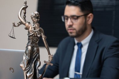 A lawyer sits in his office. He has a statue of justitia on his table.