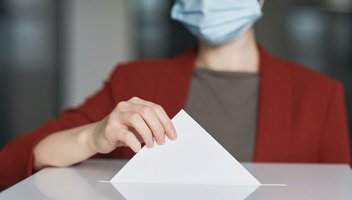 Eine Frau wirft ihren Stimmzettel in eine Wahlurne ein.